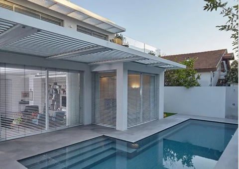 Modern white house with glass sliding doors, covered patio, and small rectangular swimming pool in backyard