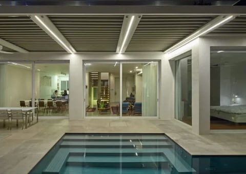 Modern home interior with sunken lap pool, glass partition walls, minimalist lighting, and open-concept living spaces